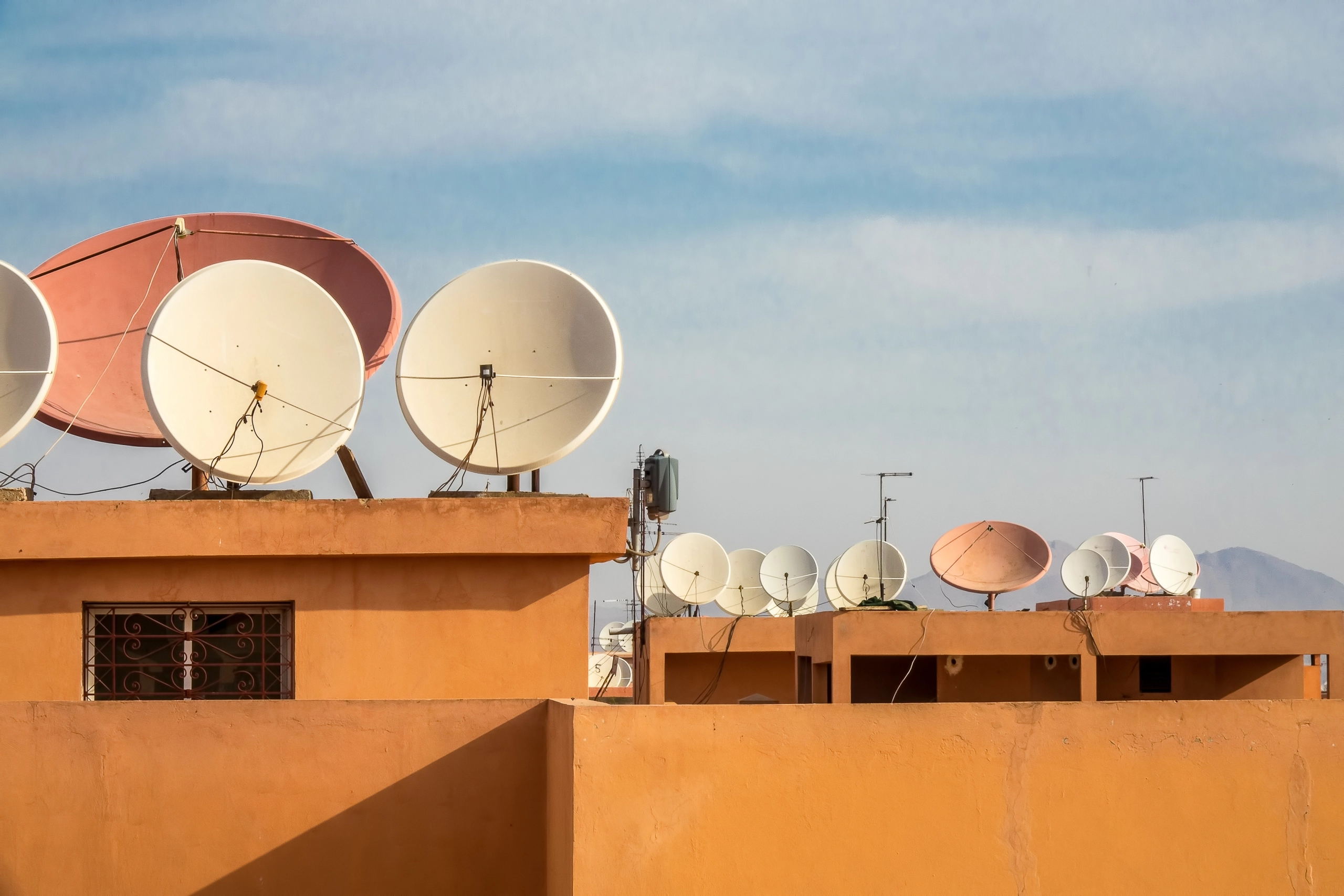 Wide angle shot of white satellite dishes on the roof of a building
