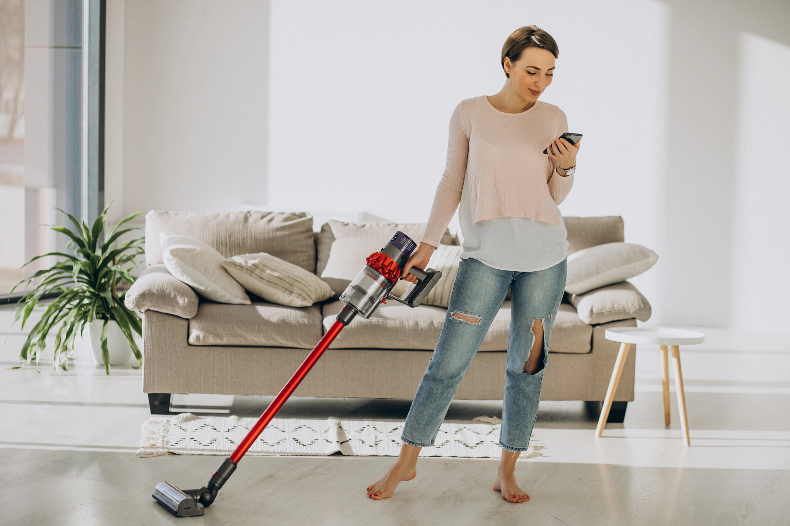 Young woman with rechargeable vacuum cleaner cleaning at home